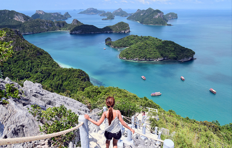 Woman looking over a cluster of awesome dark green island surrounded by the turqiouse waters
